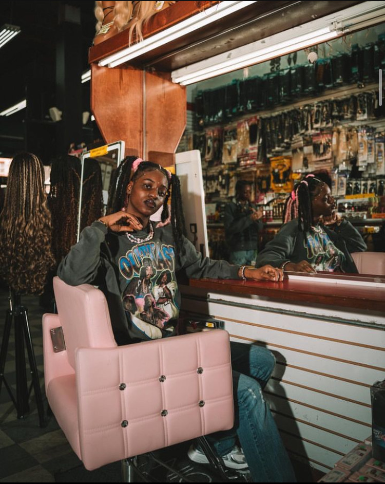 Divinity Nix-Sow sits in a pink chair in her neighborhood beauty supply store.