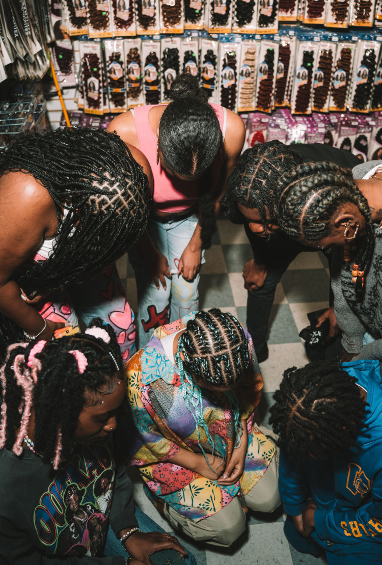 Divinity, the models, and the store clerks pose with their heads bowed down. Together they show their roots. 