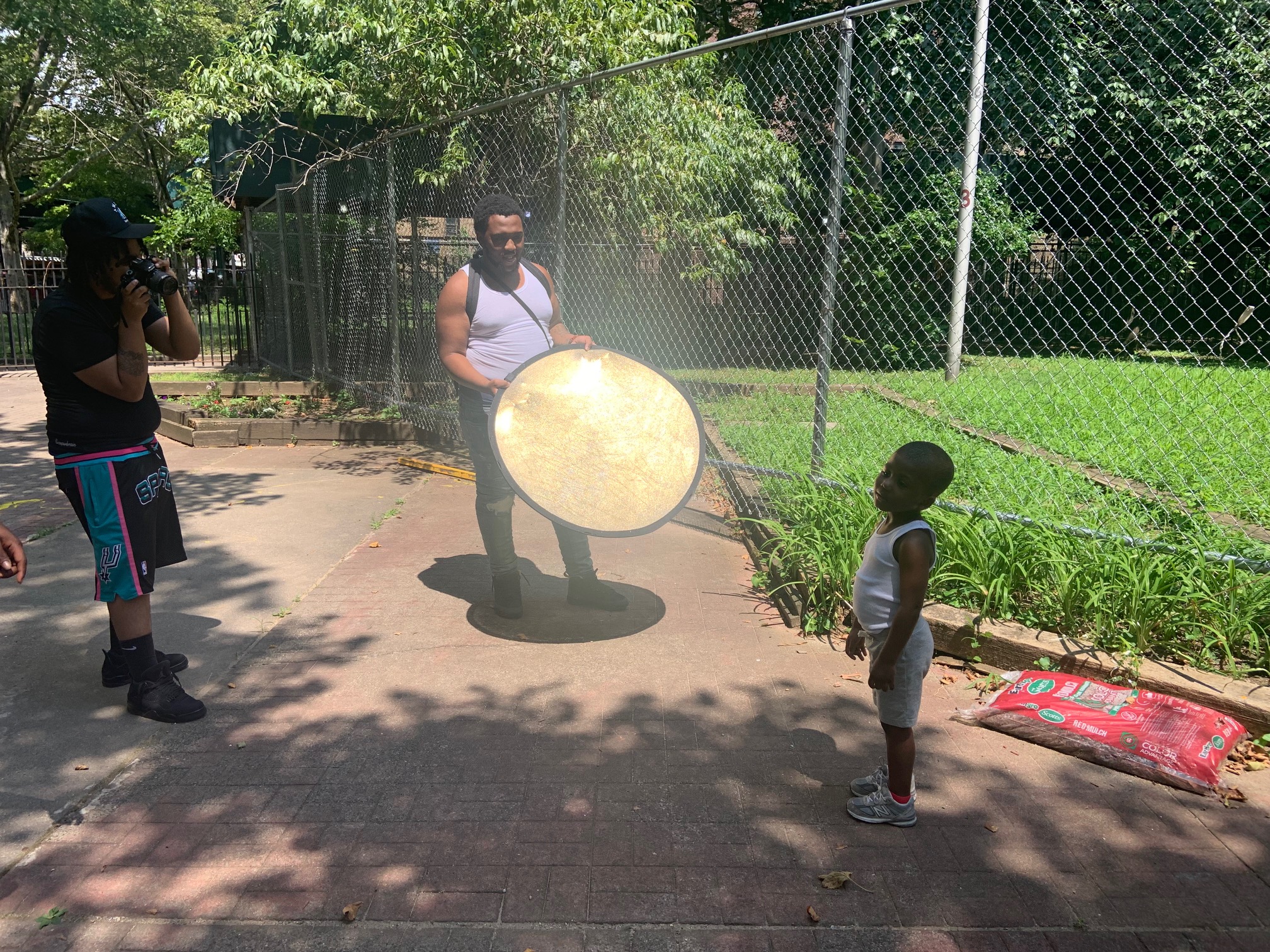 Two adults and one small child working outdoors in the community garden. 